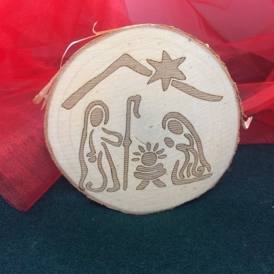 Disco de madeira gravado com presépio de Natal em fundo preto e tecido vermelho