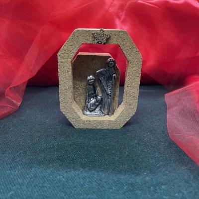 Miniatura da Sagrada Família em metal num suporte octogonal de cortiça com fundo e tecido vermelho.