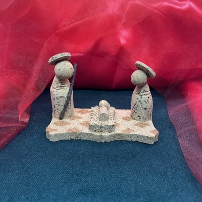 Miniatura de presépio em pedra com figuras e fundo de tecido vermelho