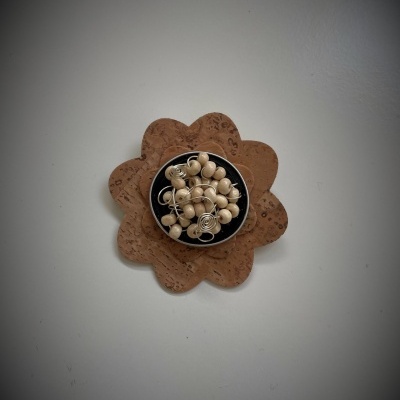 Prato preto com esferas de madeira claras e suporte flor em cortiça