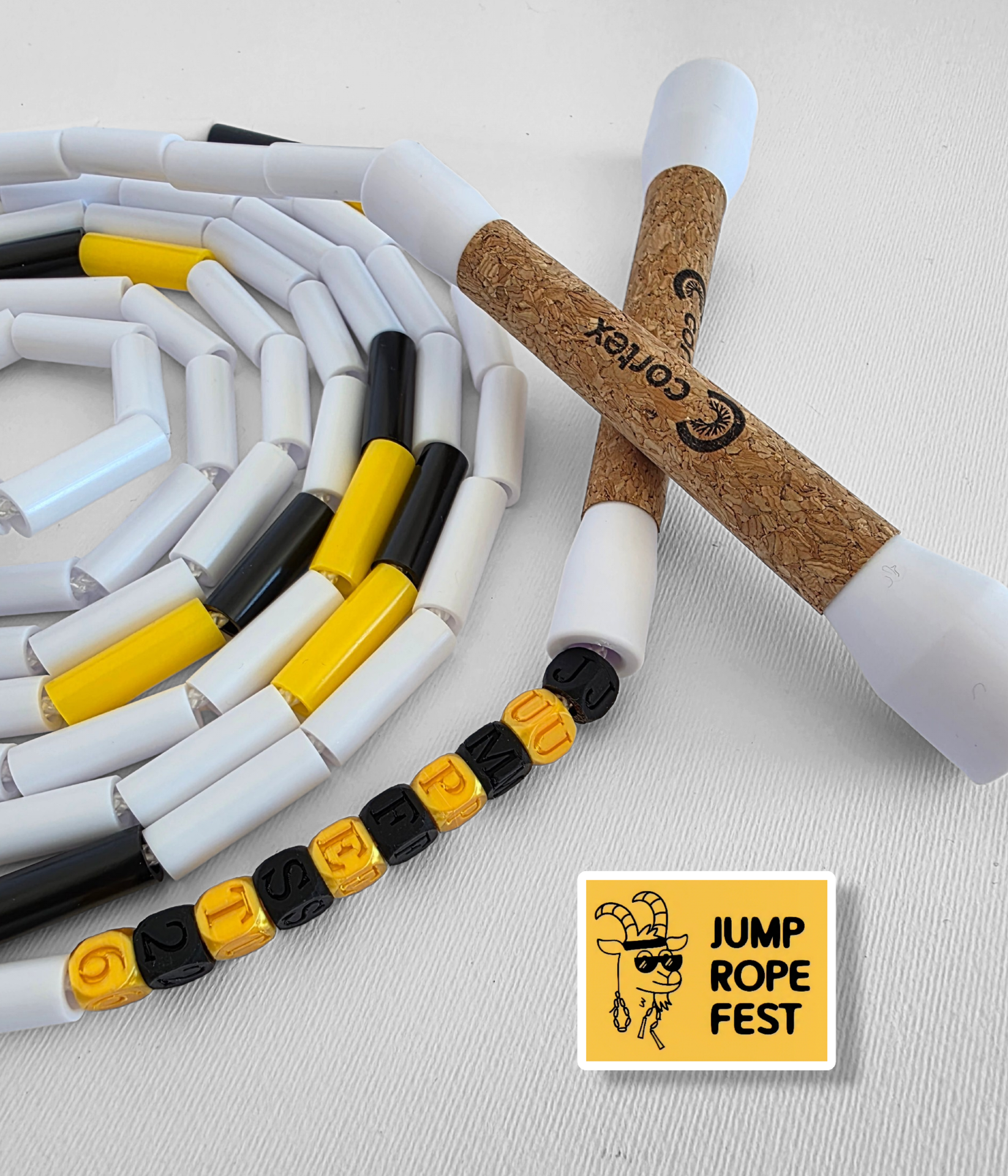 Jump rope with cork handles and colorful segmented cord, lettered beads, and yellow sticker on white background
