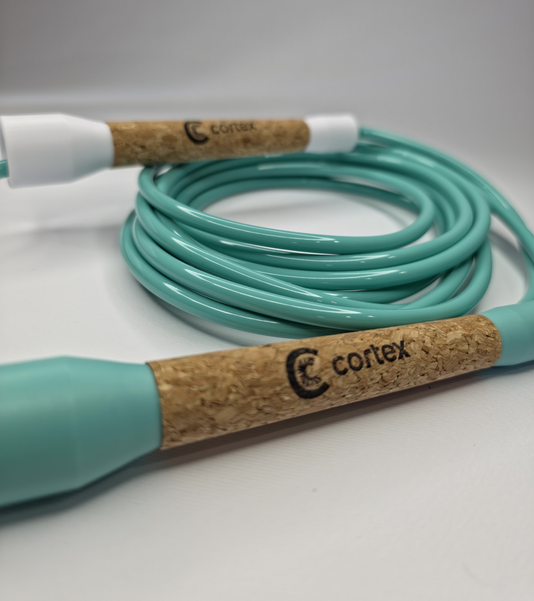 Turquoise jump rope with cork handles labeled cortex on white background