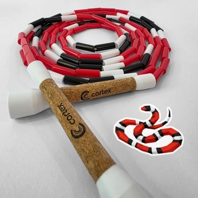 Coiled red, black, and white segmented skipping rope with cork handles printed cortex and a snake sticker on white background