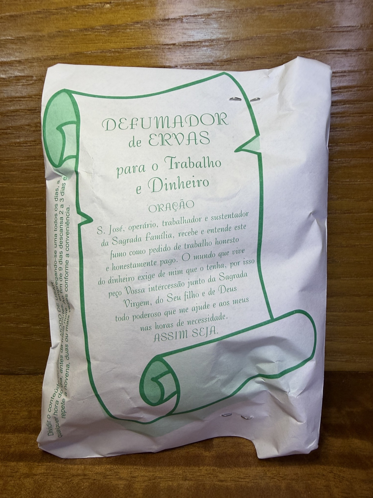 Embalagem de papel branca com texto e desenho verde sobre uma mesa de madeira.