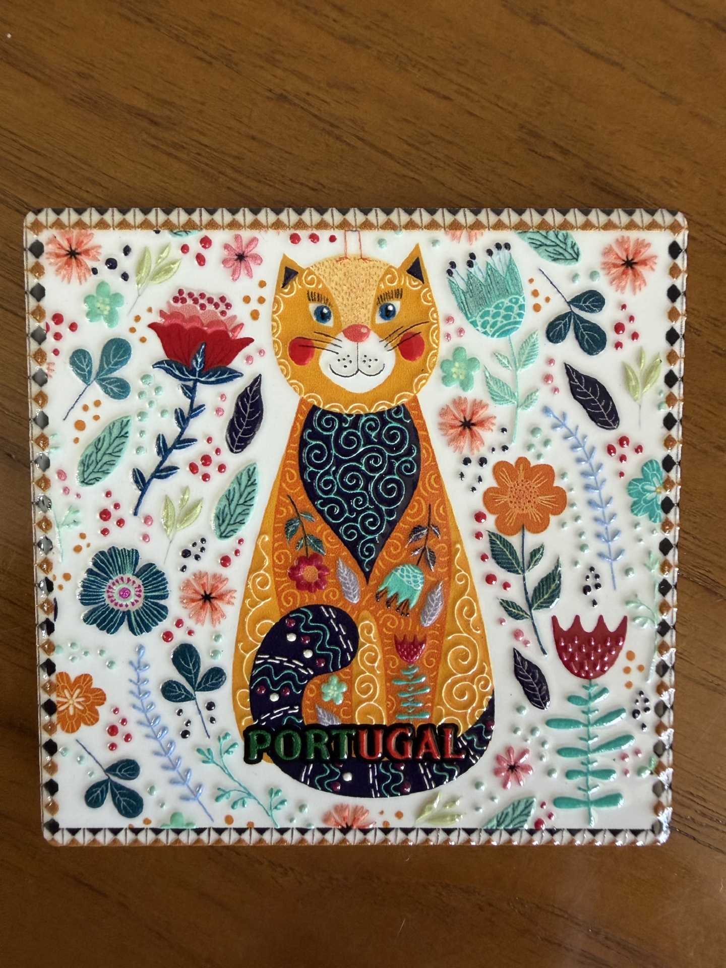 Placa decorativa com desenho colorido de gato e flores, com a palavra PORTUGAL.