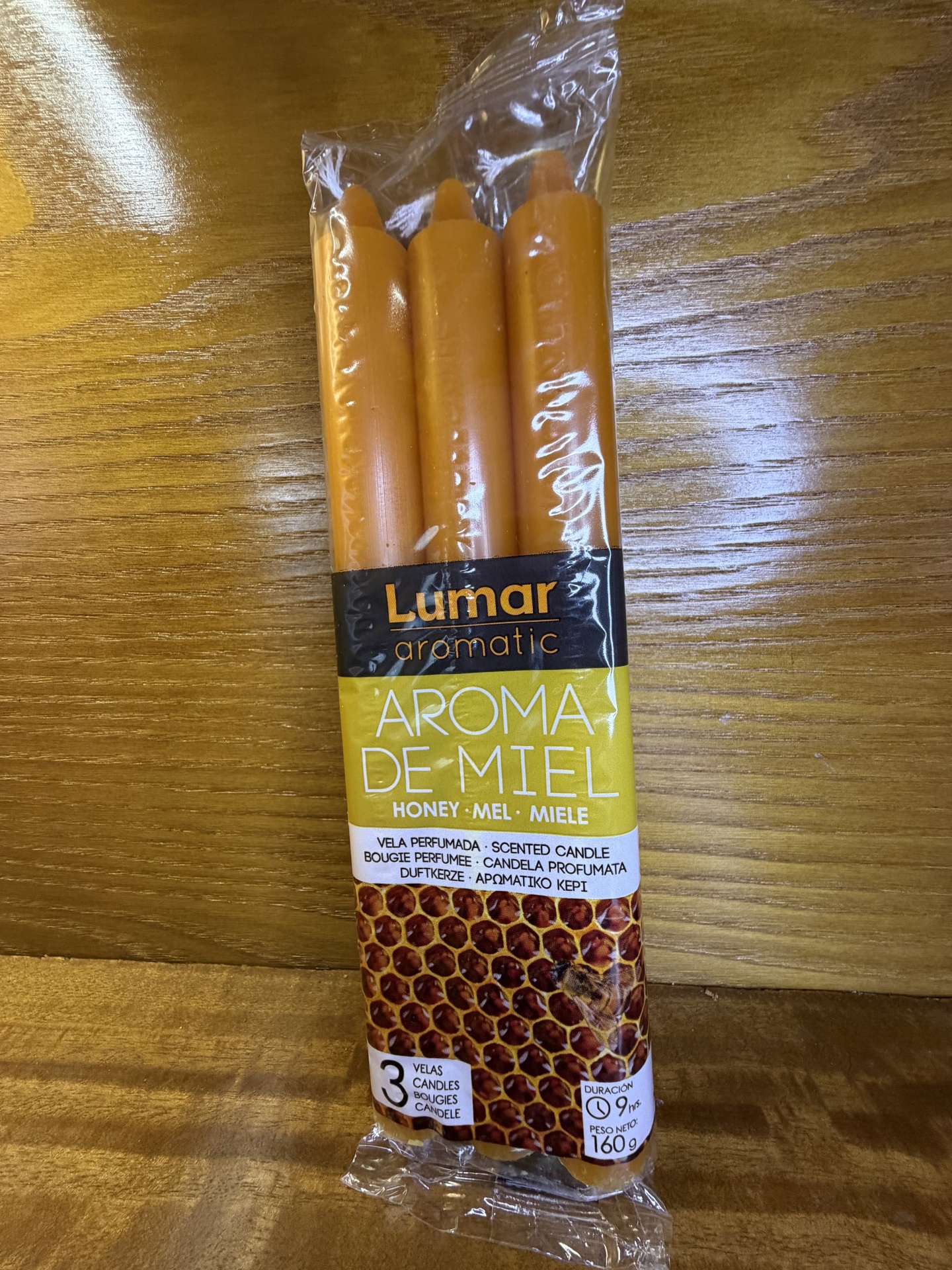 Três velas perfumadas cor laranja em embalagem plástica com rótulo aromático de mel