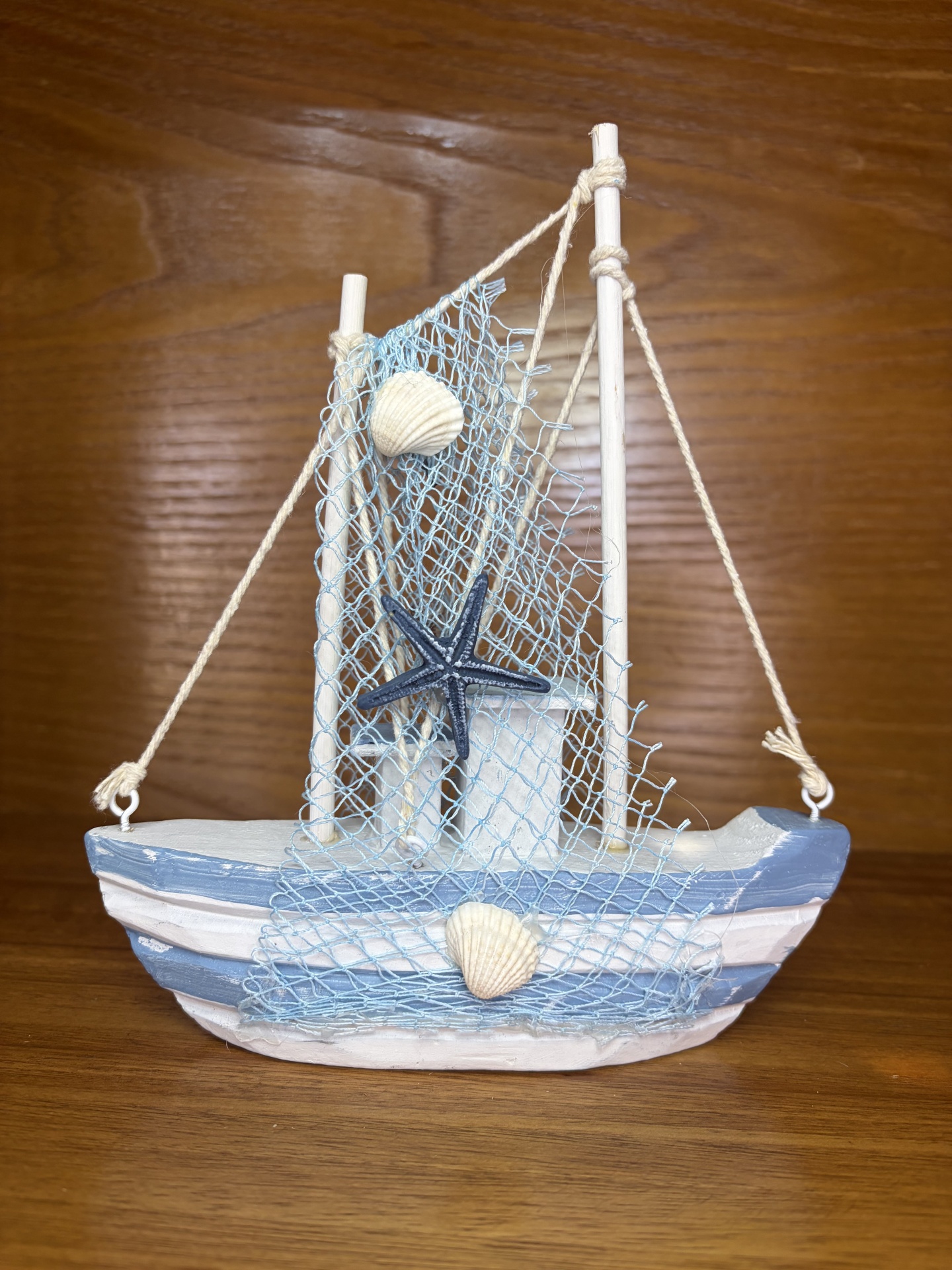 Barco decorativo em madeira azul e branca com rede azul e conchas marinhas