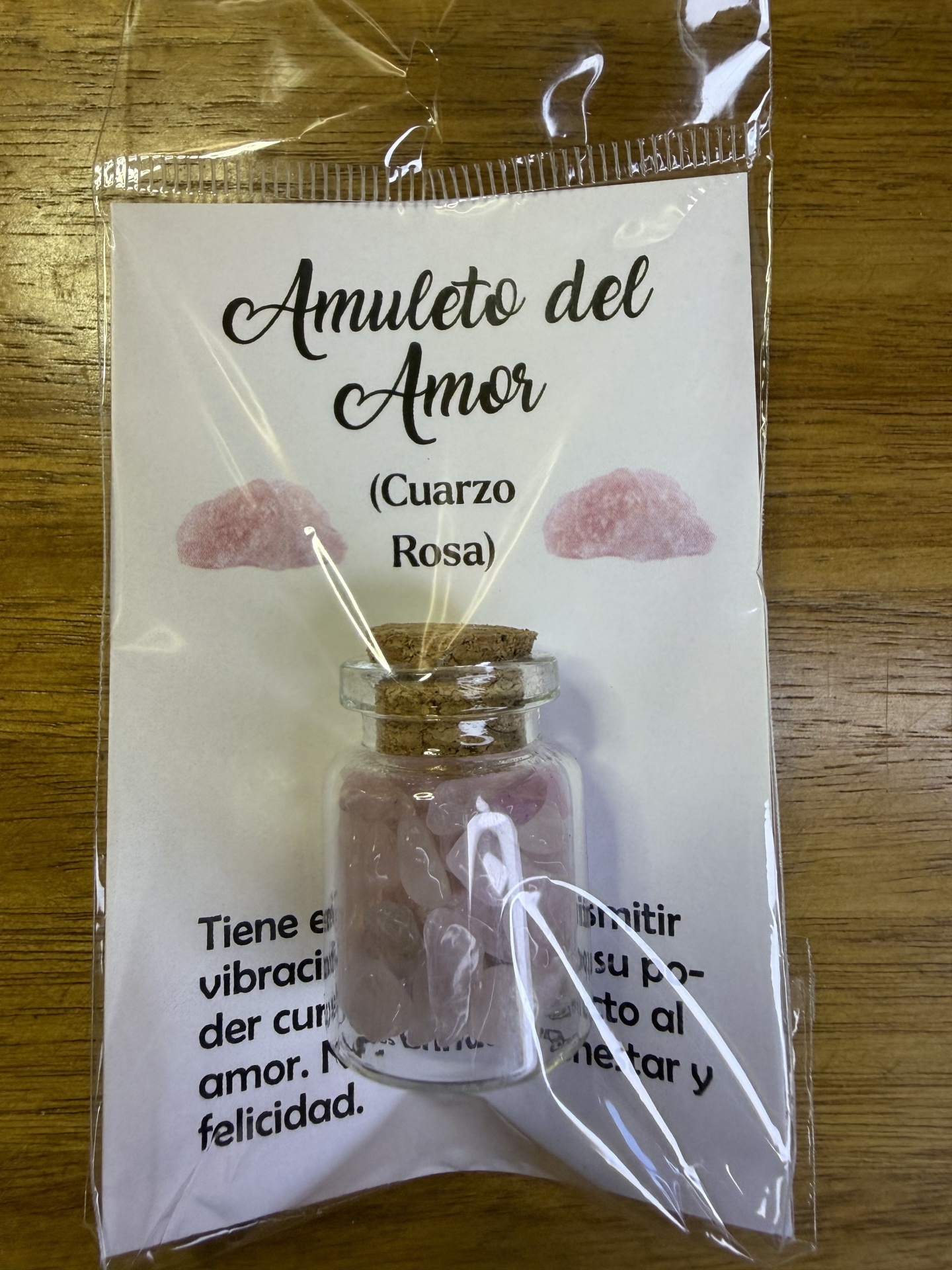 Frasco de vidro pequeno com pedras de quartzo rosa embalado com etiqueta texto Amuleto del Amor.