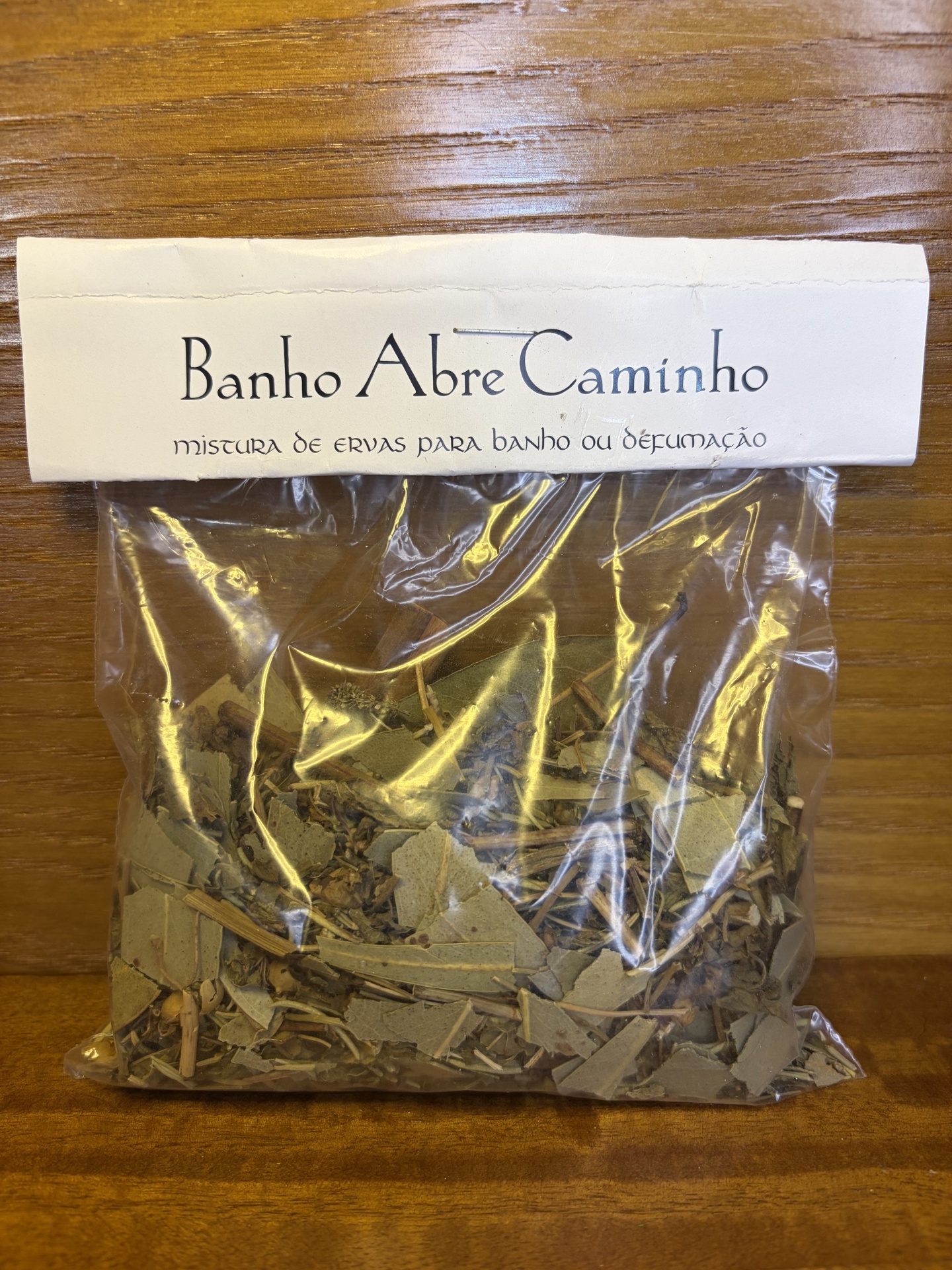 Pacote plástico com ervas secas e rótulo branco Banho Abre Caminho