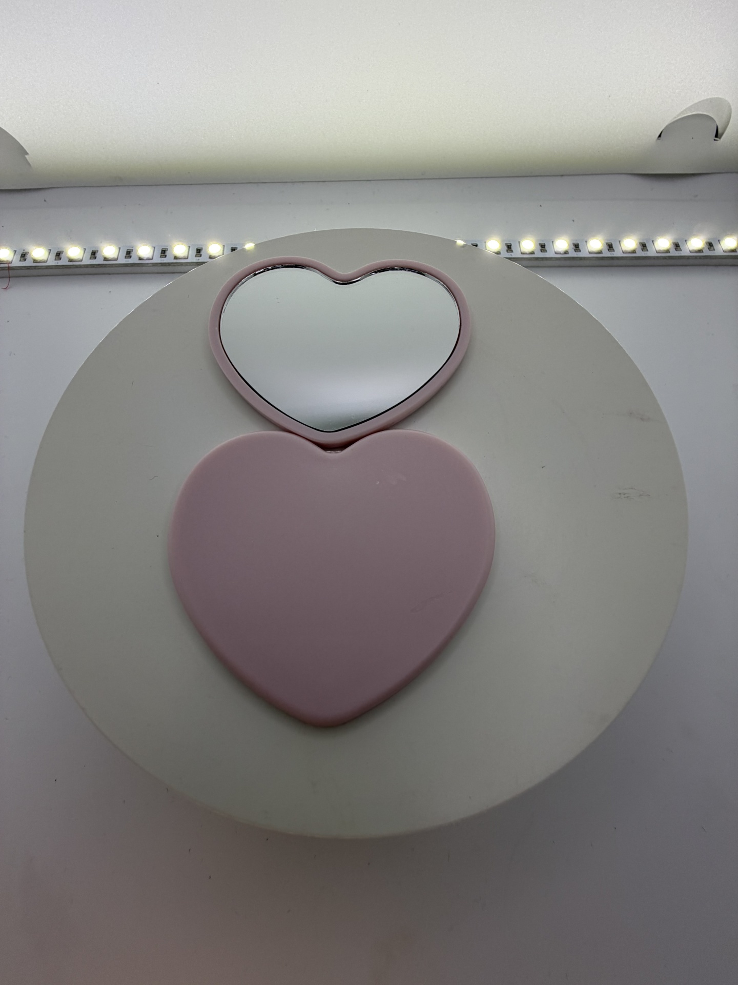 Espelho compacto em formato de coração cor-de-rosa aberto com luzes LED ao fundo