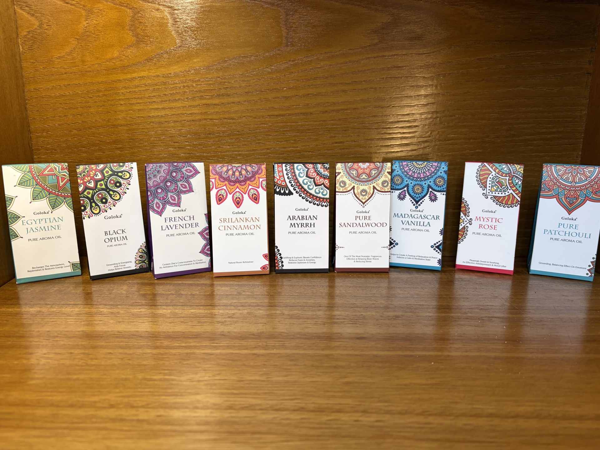 Caixas coloridas de óleos aromáticos Goloka alinhadas sobre superfície de madeira