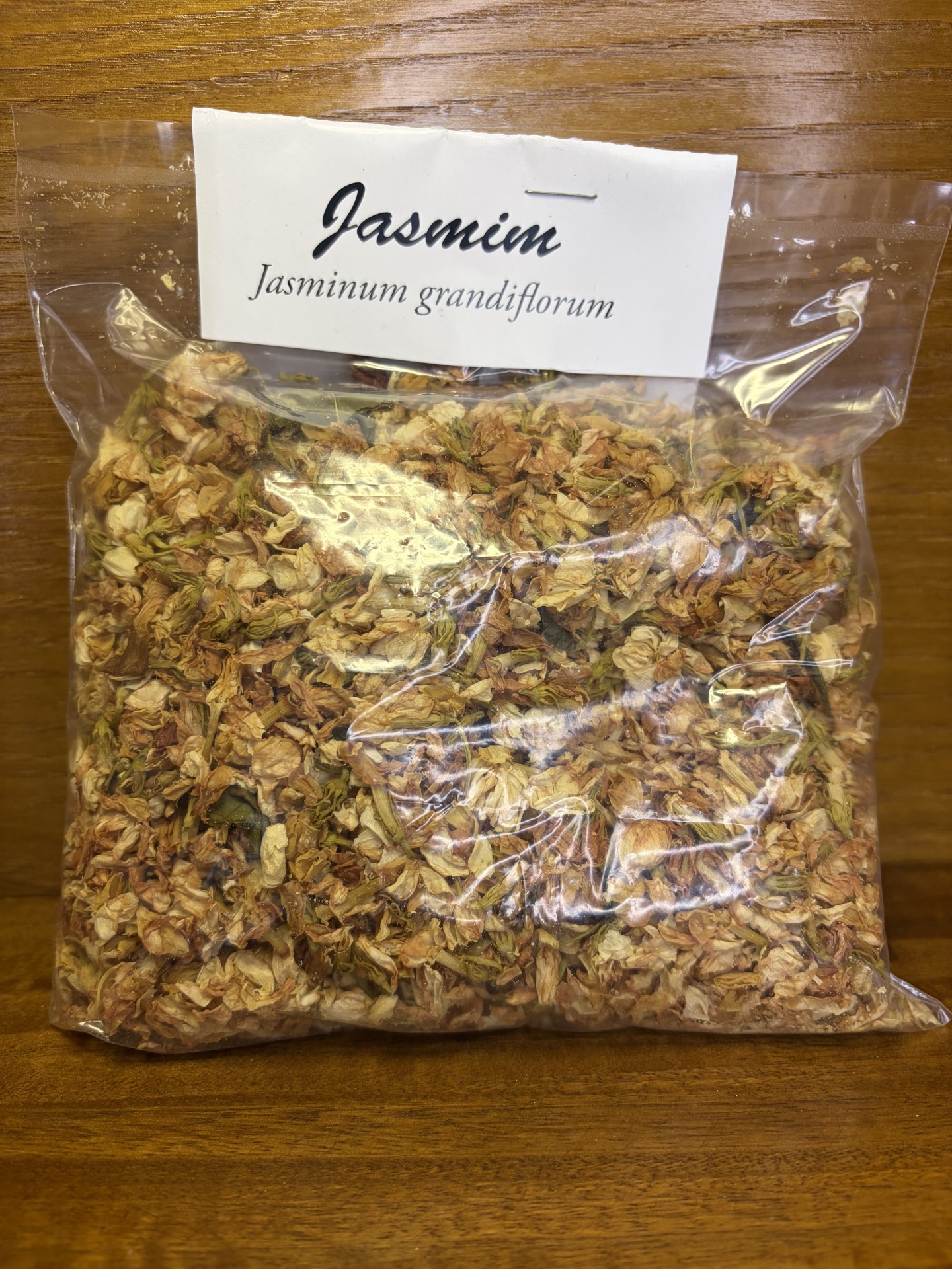 Saco plástico com flores secas e etiqueta de papel branco com texto Jasmin