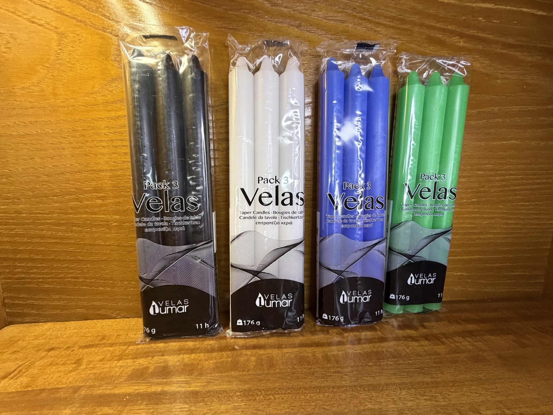 Pacote de velas de várias cores em plástico transparente em fundo de madeira