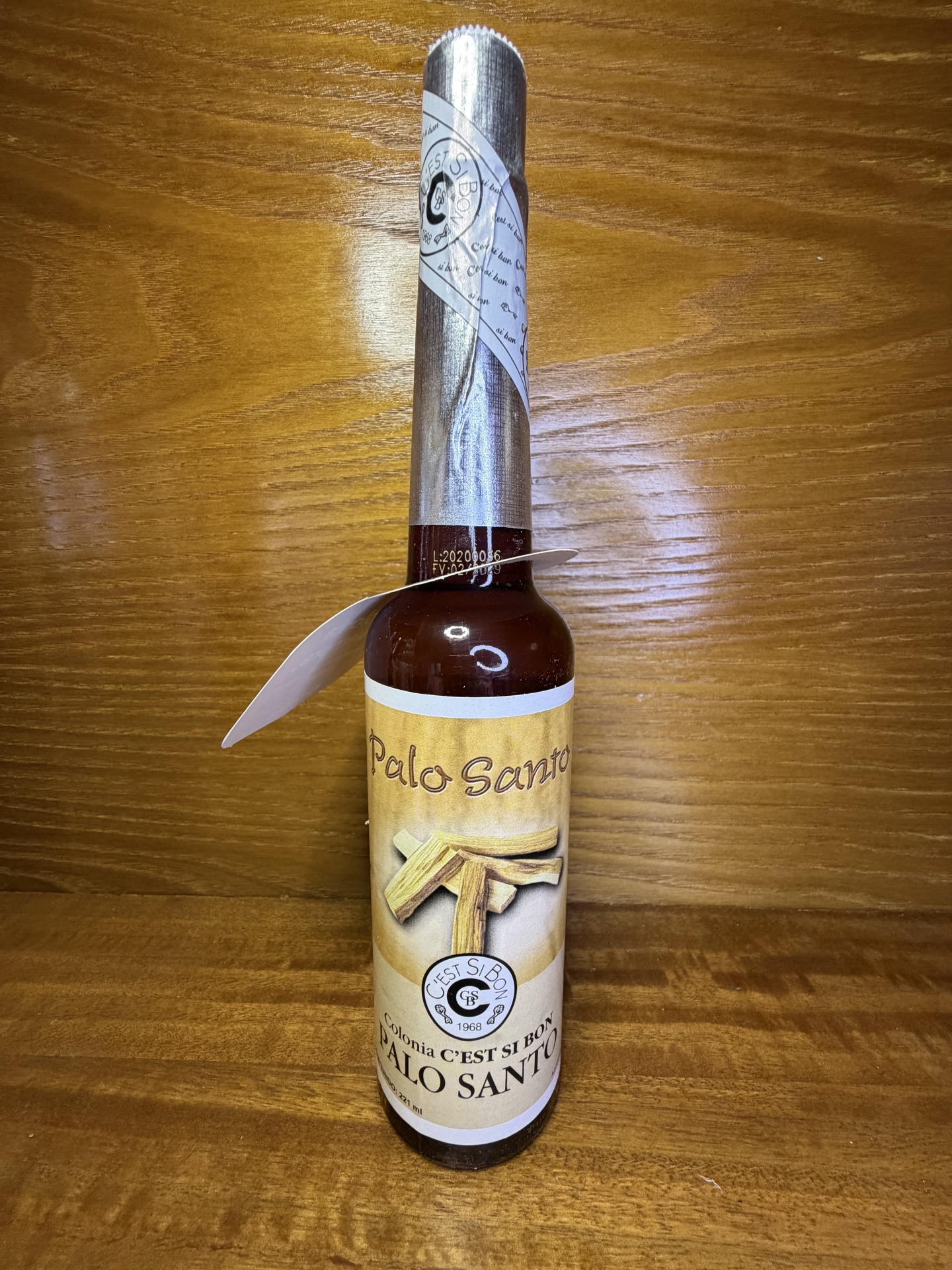 Garrafa de vidro castanha com rótulo amarelo Palo Santo e lacre prateado