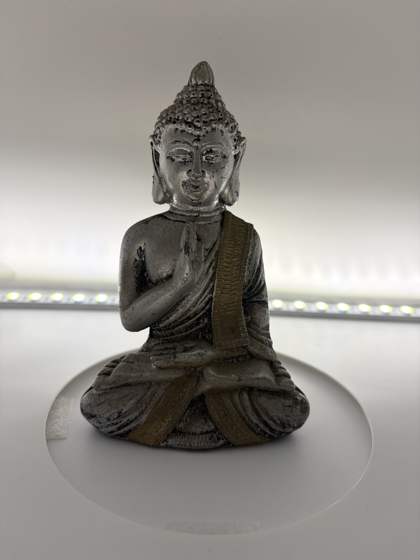 Estátua de Buda cinza envelhecida com detalhes dourados em fundo branco