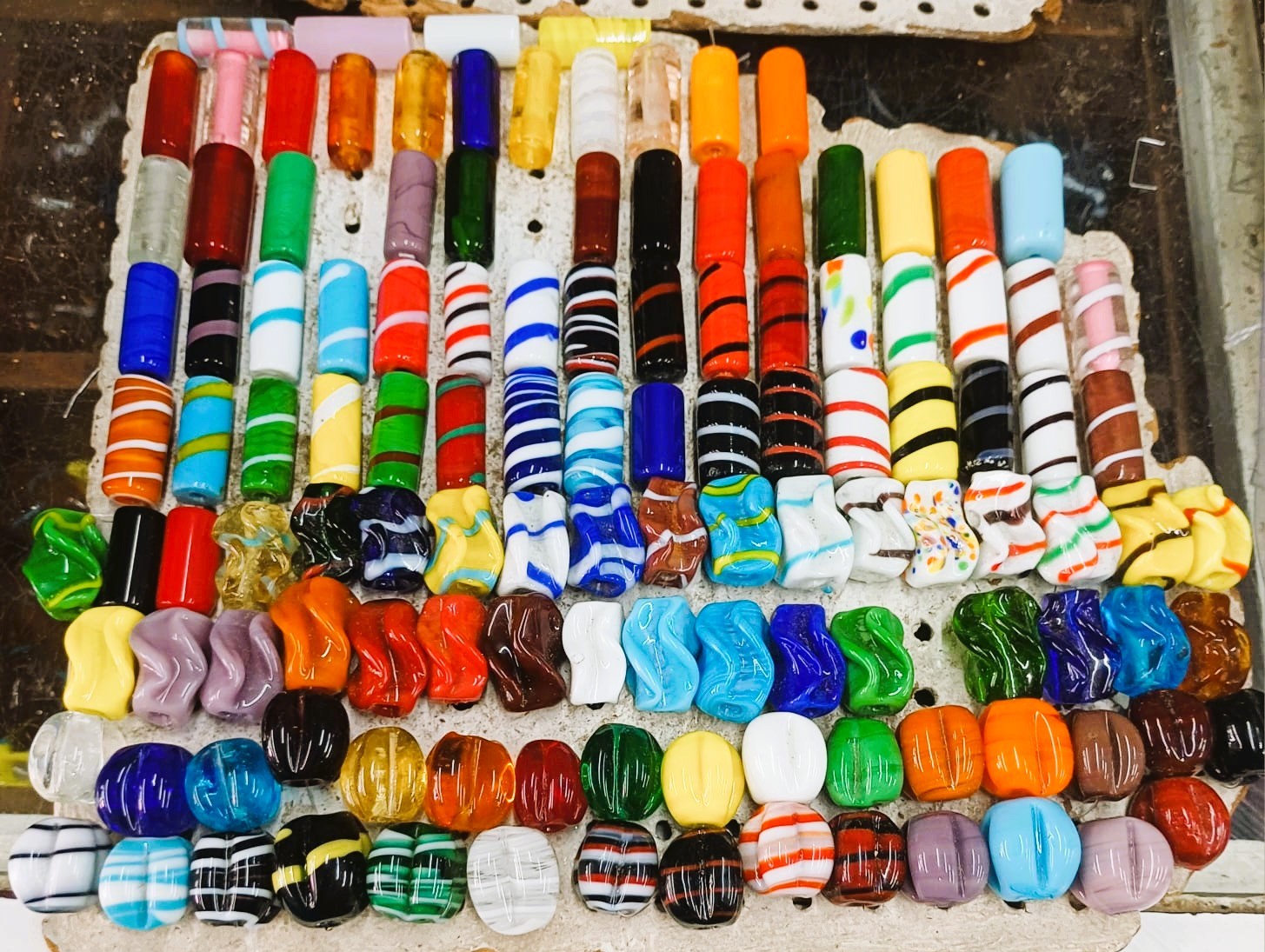Contas de vidro coloridas variadas organizadas em filas sobre mesa