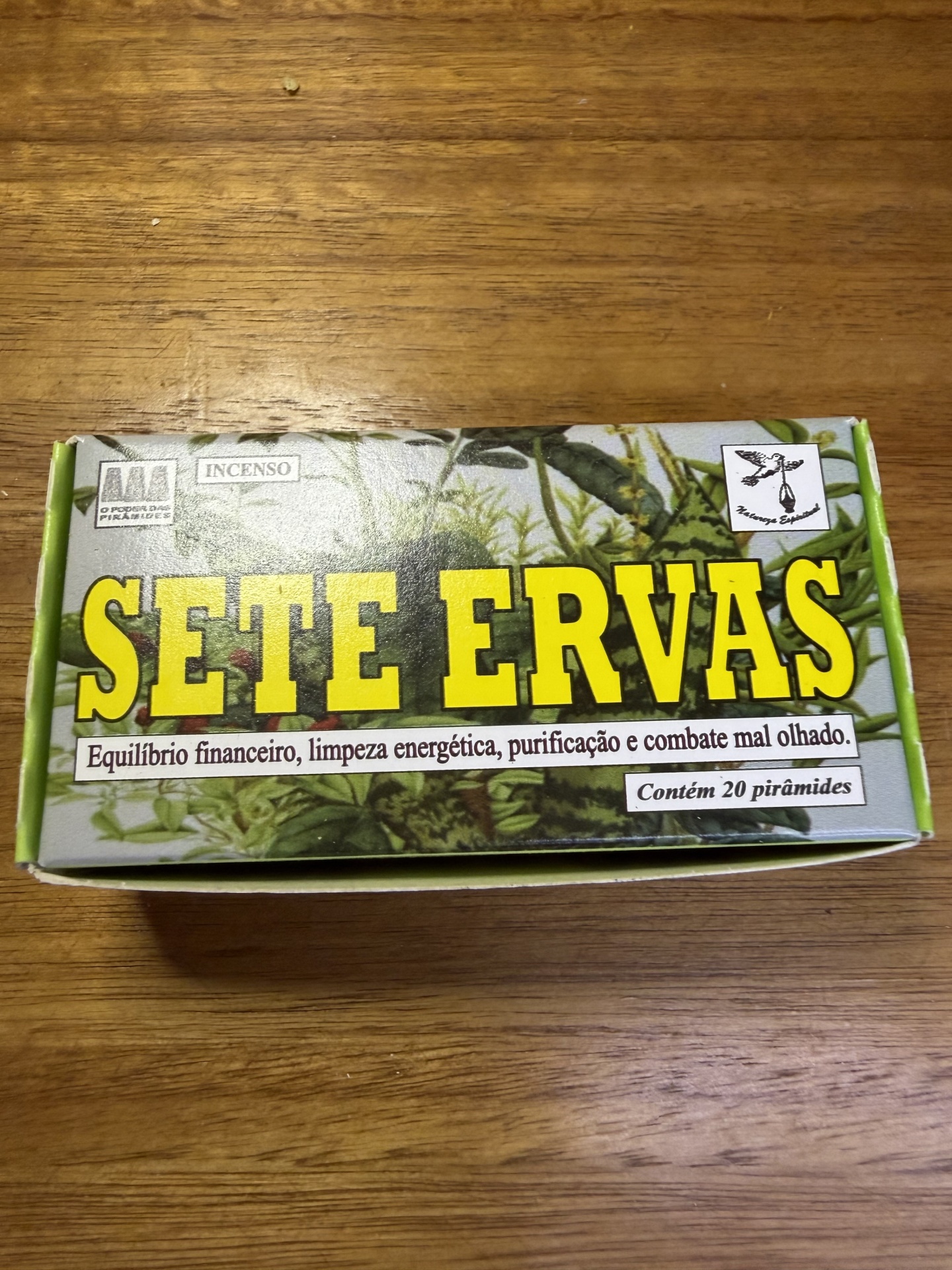 Caixa de incenso Sete Ervas com texto e plantas sobre mesa de madeira