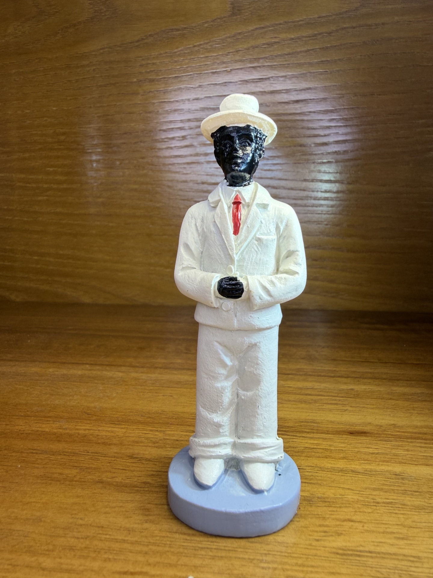 Figura decorativa de homem com fato branco e chapéu, base azul clara