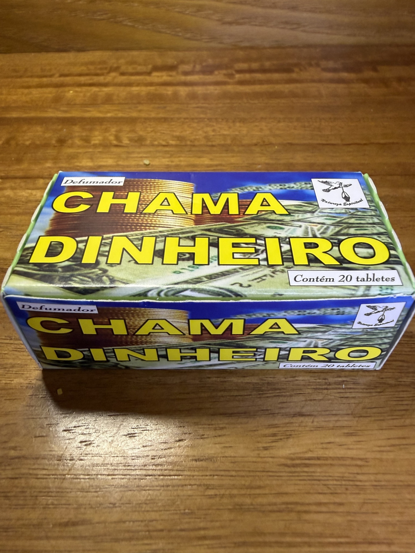 Embalagem de defumador Chama Dinheiro com 20 tabletes sobre mesa de madeira
