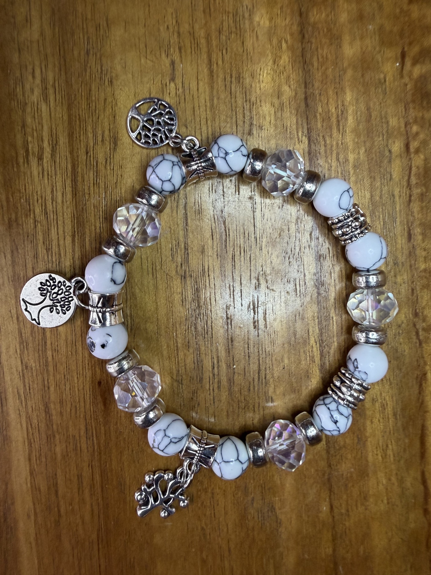 Pulseira de contas com pendentes de árvore sobre madeira