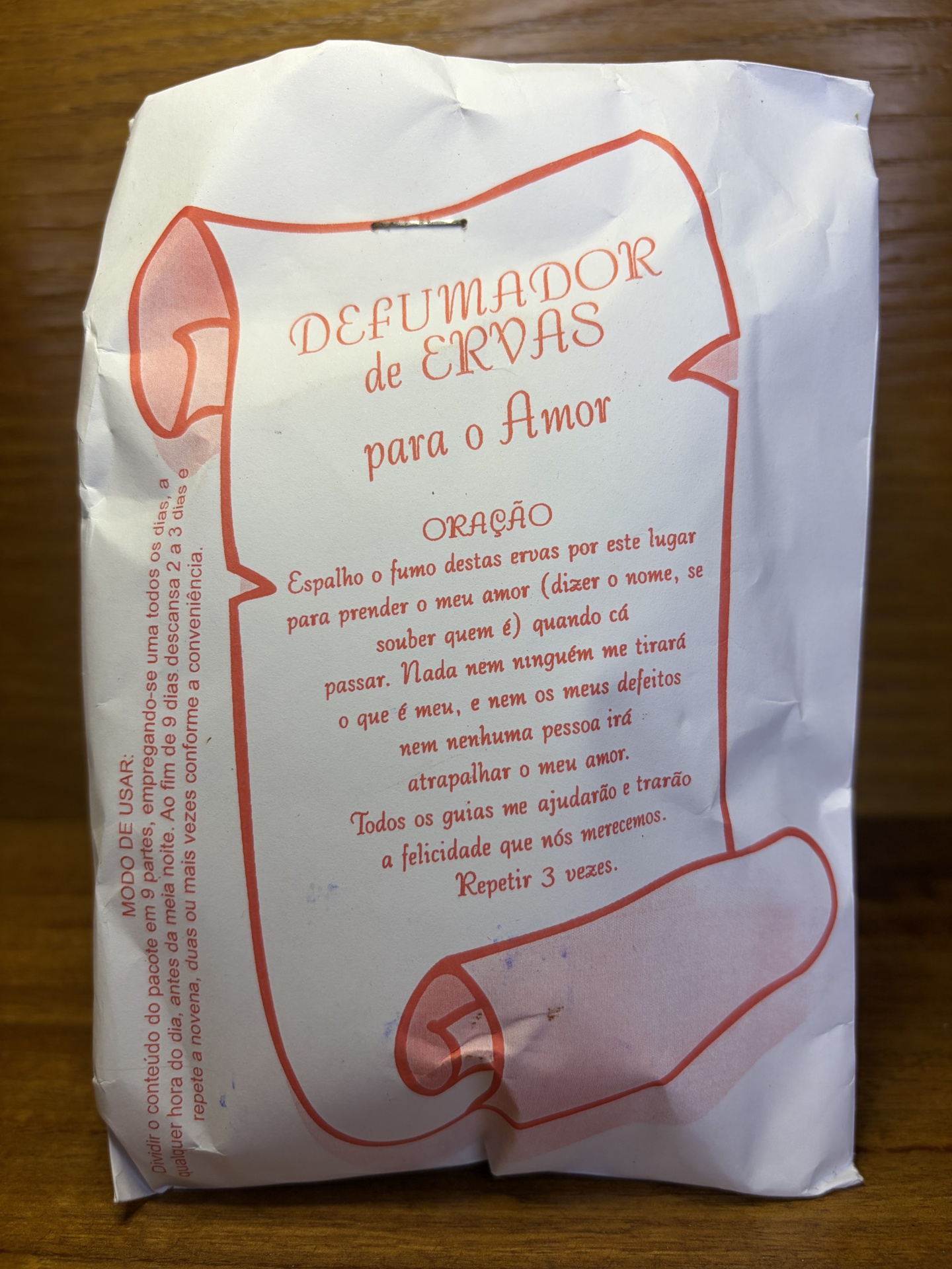Pacote de papel branco com texto impresso em vermelho e título DEFUMADOR de ERVAS para o Amor.