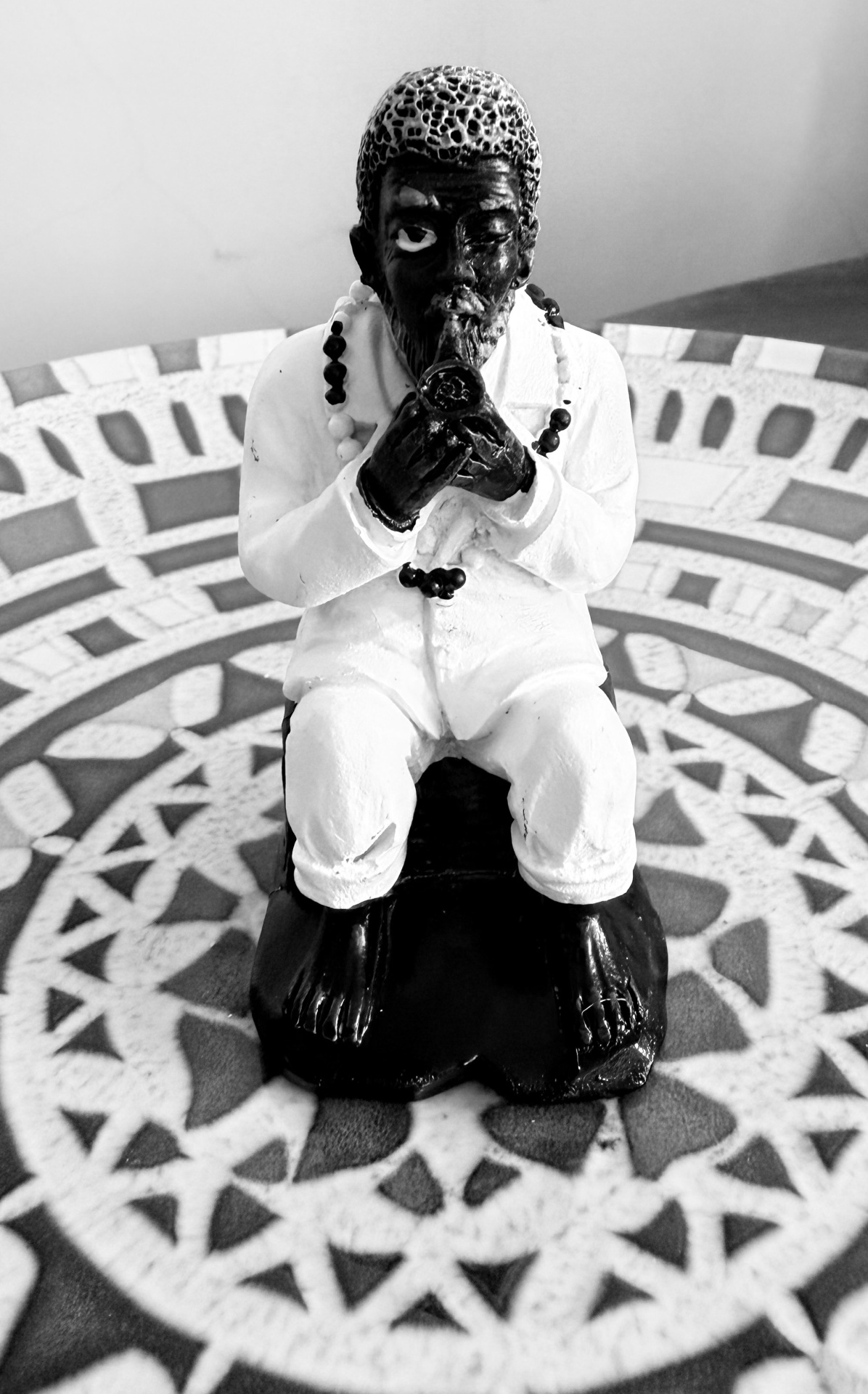 Estátua decorativa de figura masculina em preto e branco com fundo decorativo