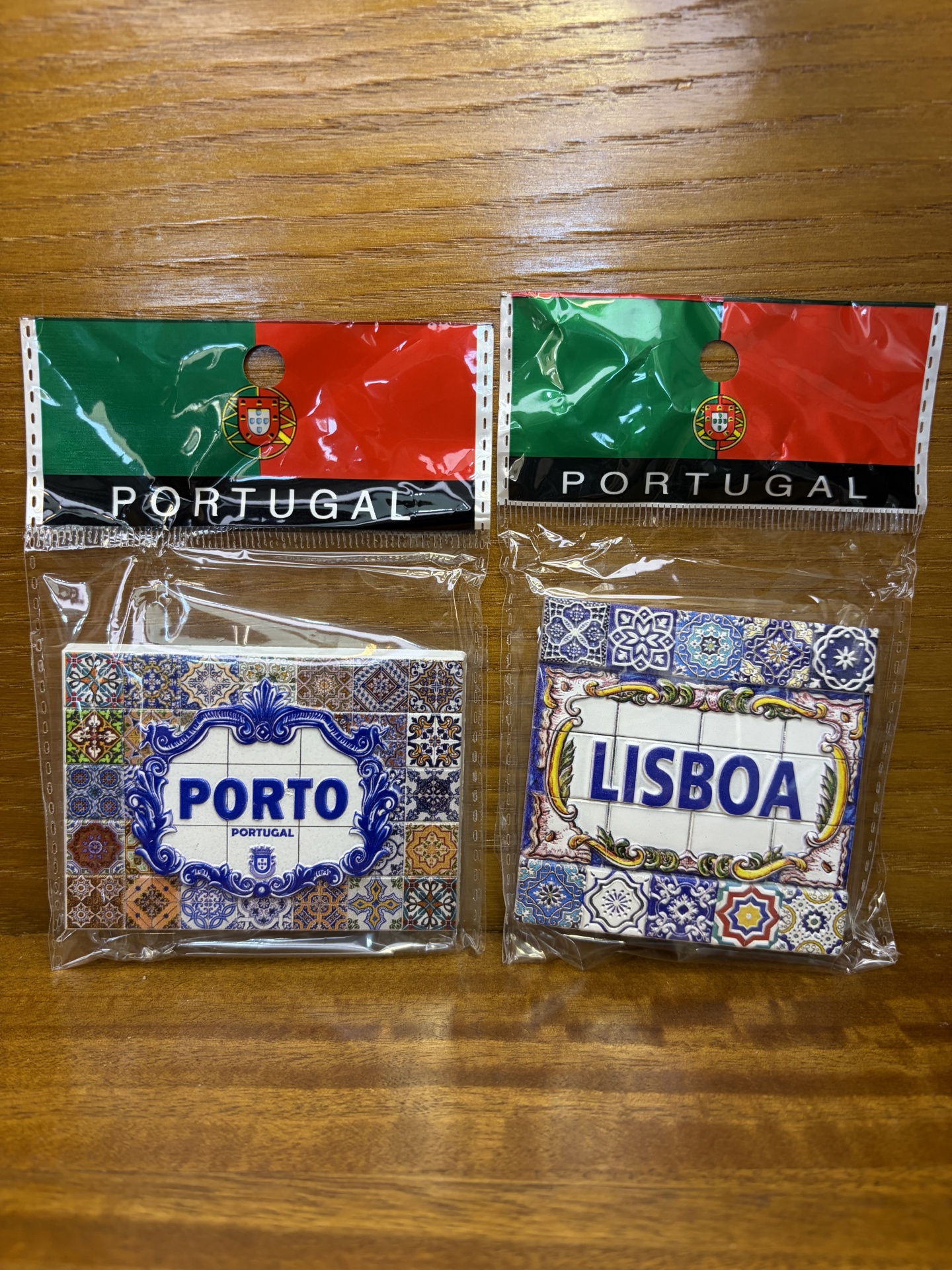 Dois ímanes portugueses com tema de azulejos, em embalagens plásticas com a bandeira de Portugal e texto PORTUGAL.