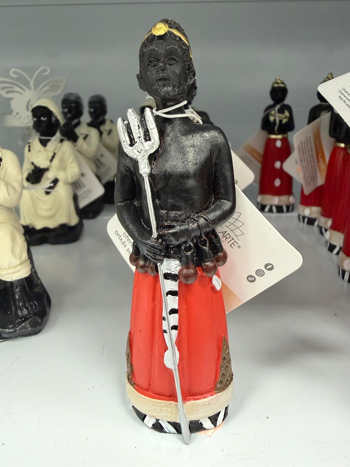 Estátua decorativa de figura masculina com tridente e roupa vermelha.