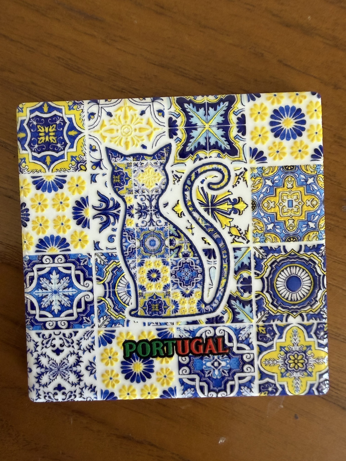 Azulejo decorativo azul, amarelo e branco com forma de gato e palavra PORTUGAL