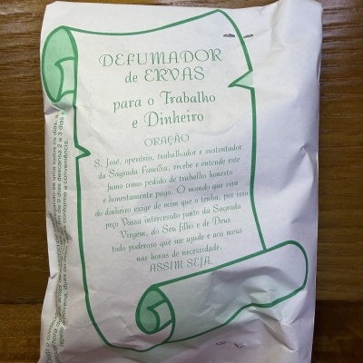 Embalagem de papel branca com texto e desenho verde sobre uma mesa de madeira.