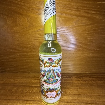 Garrafa de vidro com líquido amarelo claro e rótulo floral colorido