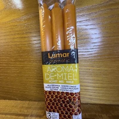 Três velas perfumadas cor laranja em embalagem plástica com rótulo aromático de mel