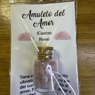 Frasco de vidro pequeno com pedras de quartzo rosa embalado com etiqueta texto Amuleto del Amor.