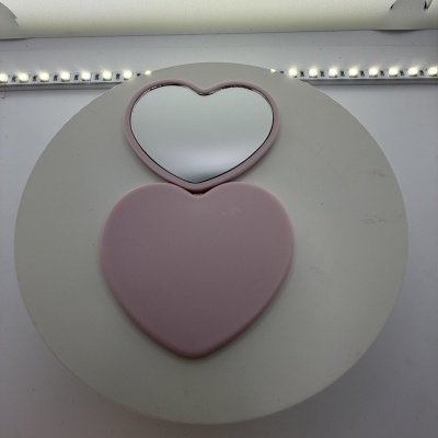 Espelho compacto em formato de coração cor-de-rosa aberto com luzes LED ao fundo