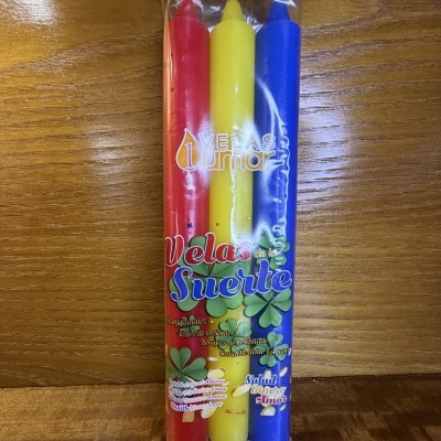 Conjunto de três velas coloridas (vermelha, amarelo e azul) embaladas em plástico transparente com texto visível