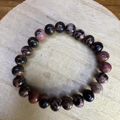 Pulseira com contas rosa e pretas em superfície de madeira clara