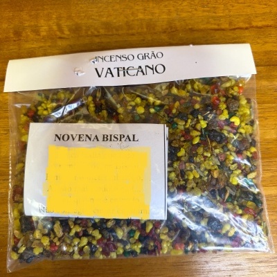 Pacote de resina colorida para incenso com etiquetas VATICANO e NOVENA BISPAL sobre mesa de madeira