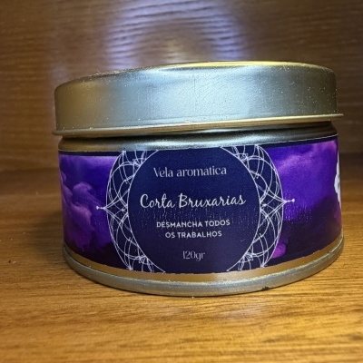 Frasco metálico com rótulo roxo de vela aromática Corta Bruxarias sobre madeira