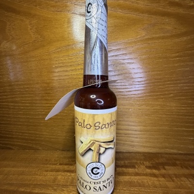 Garrafa de vidro castanha com rótulo amarelo Palo Santo e lacre prateado
