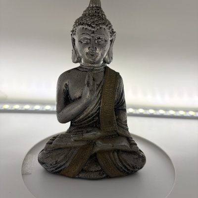 Estátua de Buda cinza envelhecida com detalhes dourados em fundo branco