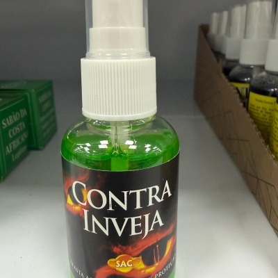 Frasco de spray contra inveja com líquido verde em prateleira