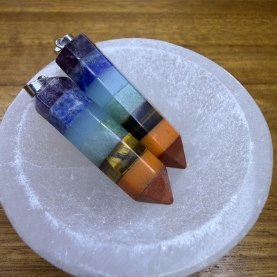 Dois pendentes triangulares multicoloridos dentro de tigela branca sobre mesa de madeira