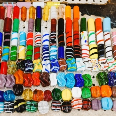Contas de vidro coloridas variadas organizadas em filas sobre mesa