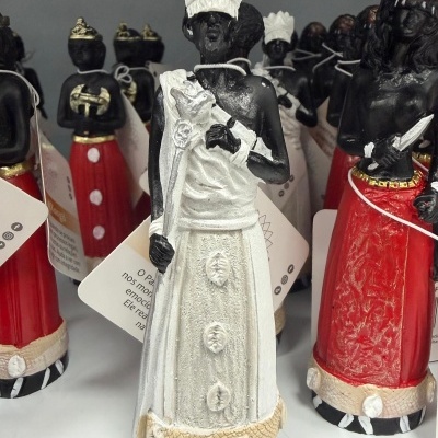 Figuras decorativas de homens negros com roupas brancas e vermelhas e coroas em uma prateleira