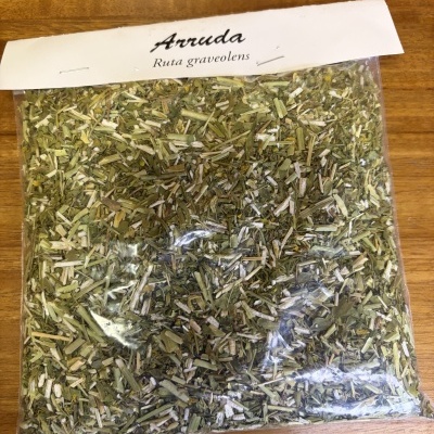 Pacote plástico com ervas secas Arruda Ruta graveolens sobre madeira