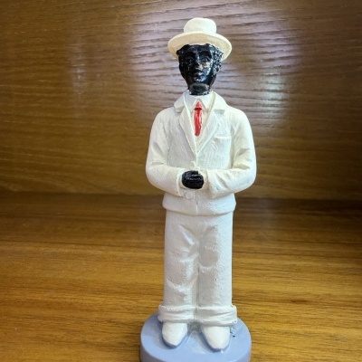 Figura decorativa de homem com fato branco e chapéu, base azul clara