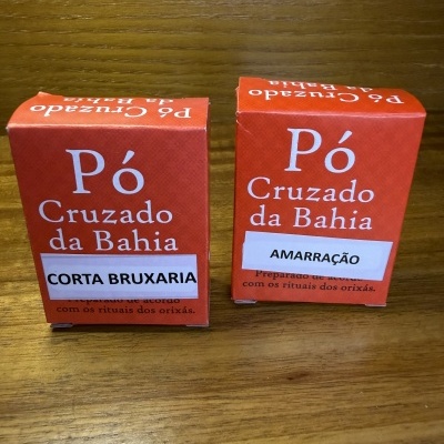 Caixas vermelhas de pó Cruzado da Bahia com etiquetas CORTA BRUXARIA e AMARRAÇÃO