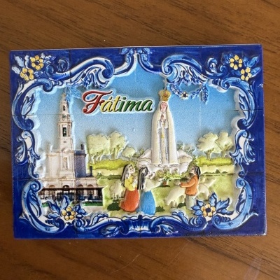 Azulejo decorativo da Basílica de Fátima com moldura azul e figuras humanas em cerâmica