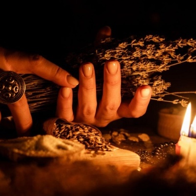 Mãos segurando ramos secos, grãos, pão com manteiga e velas acesas