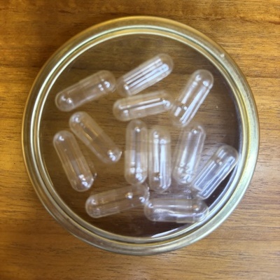 Cápsulas transparentes num prato de vidro sobre madeira clara